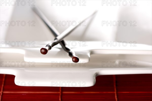 Wooden chopsticks & white plate on bamboo placemat