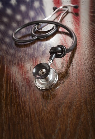 Knotted stethoscope with american flag reflection on wooden table