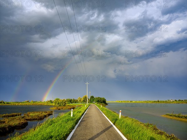 Clouds and rainbow over single lane road