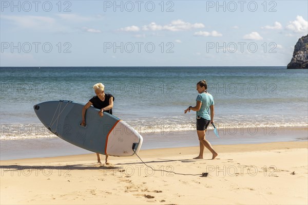 Two female friends enjoying stand up paddling on the Atlantic Ocean in Portugal