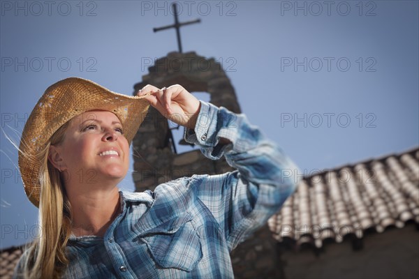 Beautiful cowgirl portrait with old church and cross behind