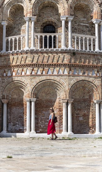 Young woman in red dress standing in front of Basilica dei Santi Maria e Donato
