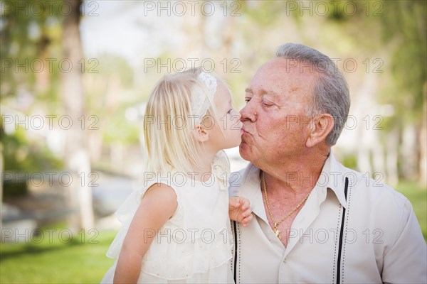 Loving grandfather and granddaughter kissing outside at the park