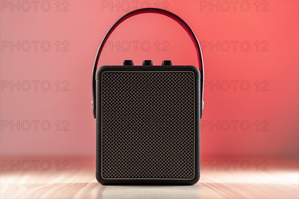 Black modern bluetooth loudspeaker on a reddish background