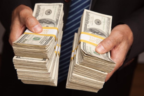 Businessman handing over stacks of hundred dollar bills