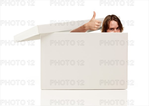 Young man with thumbs up and popping his head out from a blank white box isolated on a white background