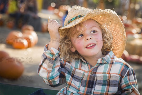 Adorable little boy wearing cowboy hat at pumpkin patch farm