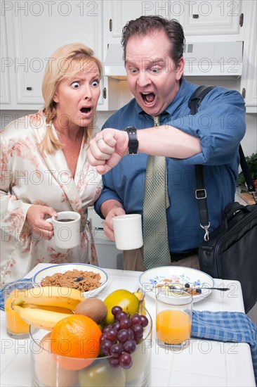 Late for work stressed couple checking time in kitchen