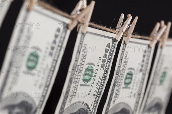 Hundred dollar bills hanging from a clothesline on a dark background
