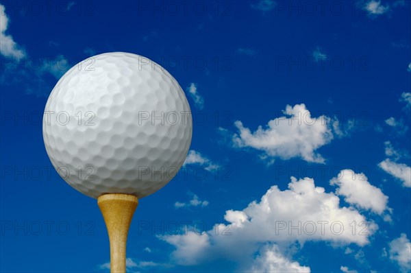 Golf ball & tee with clouds and sky background