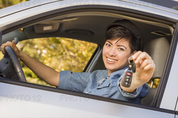 Happy smiling mixed-race woman in car holding set of keys