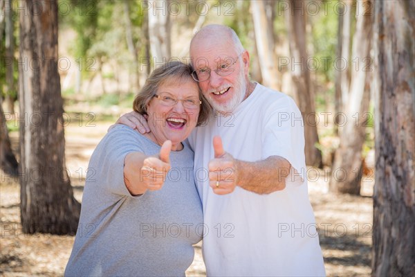 Happy senior couple with thumbs up outdoors