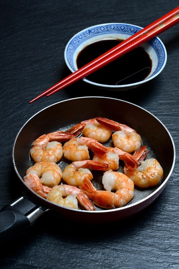 Fried prawns in pan and small bowl with soy sauce