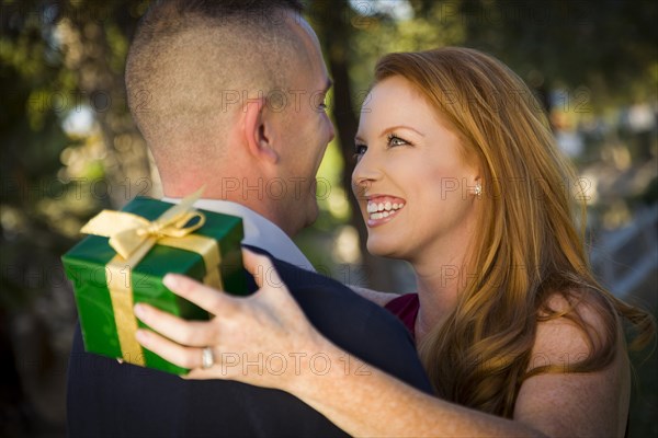 Smiling beautiful young woman and handsome military man exchange a christmas gift