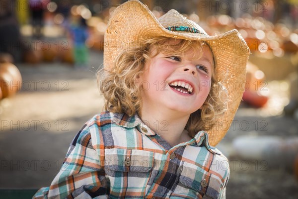 Adorable little boy wearing cowboy hat at pumpkin patch farm