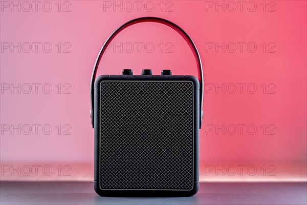 Black modern bluetooth loudspeaker on a pinkish background