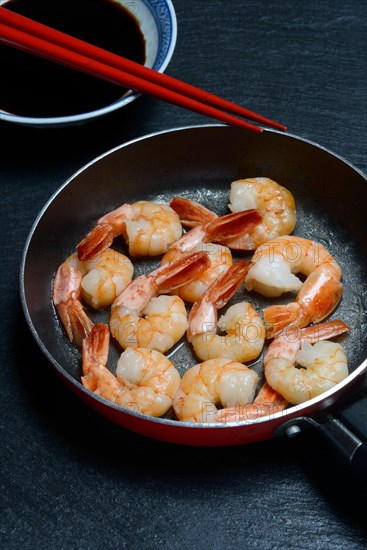 Fried prawns in pan and small bowl with soy sauce