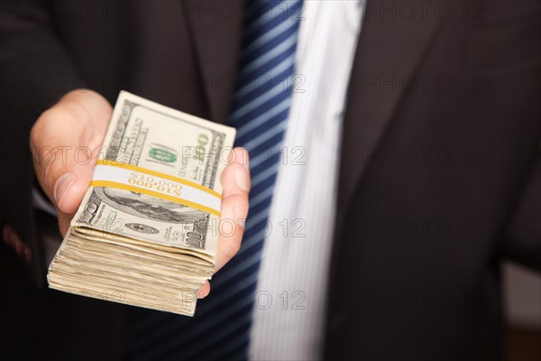 Businessman handing over stack of one hundred dollar bills