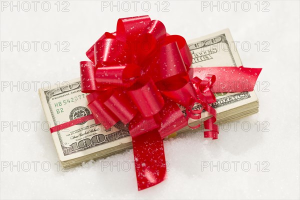 Stack of one hundred dollar bills with red ribbon on snow flakes