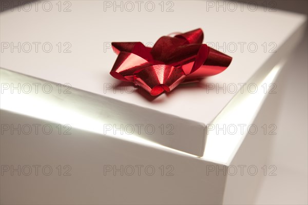 Gift box with red bow lid revealing very bright contents on a gradated background