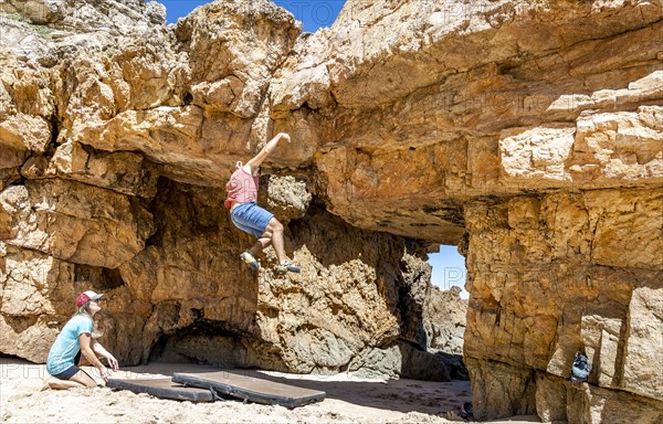 A climber falling off the rock on safety mats on the beach