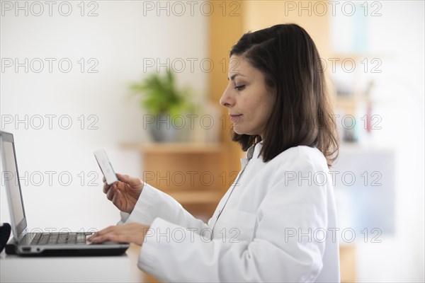 Pharmacist with medicine in a pharmacy working with modern technology and smock