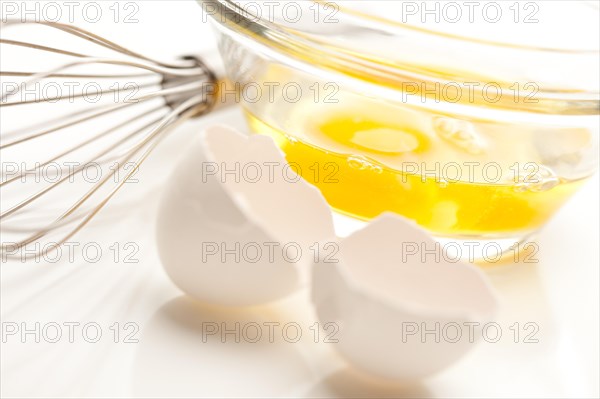 Hand mixer with eggs in a glass bowl on a reflective white background