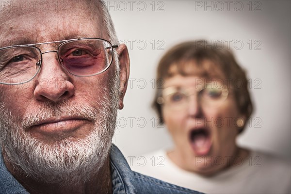 Battered and scared man with screaming angry woman behind