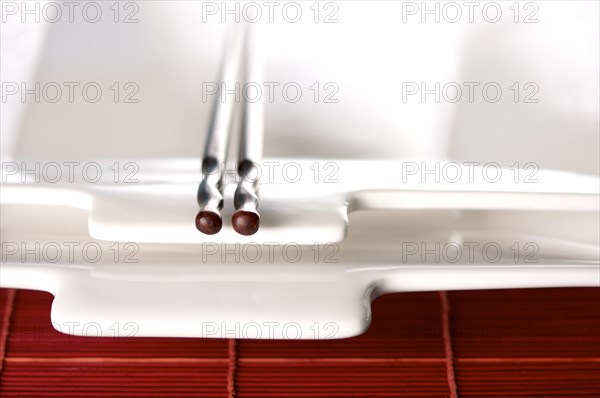 Wooden chopsticks & white plate on bamboo placemat