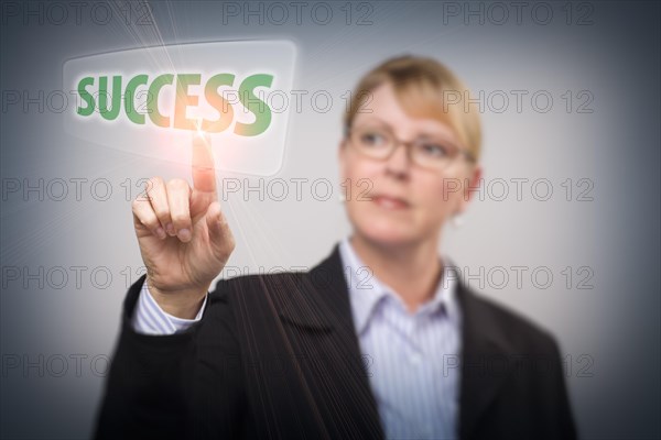Attractive blonde woman pushing success button on an interactive touch screen