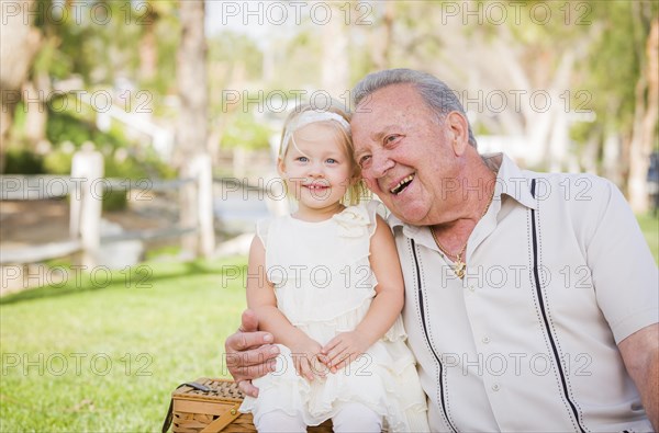 Loving grandfather and granddaughter hugging outside at the park