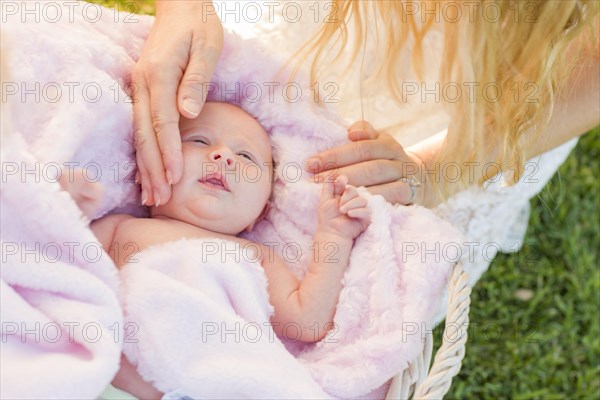 Gentle hands of mother caressing her newborn baby girl in pink blanket