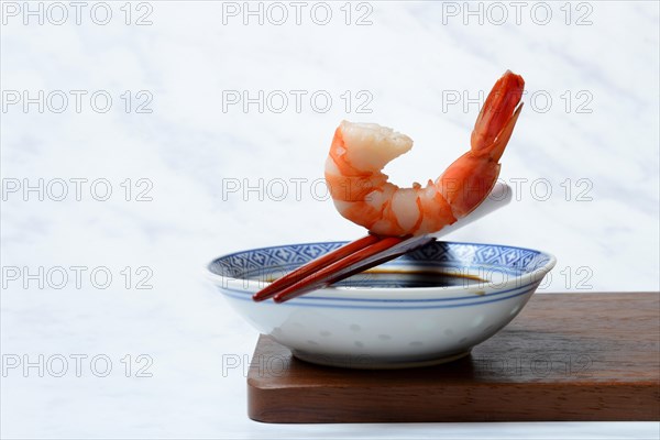 Cooked shrimp on chopsticks and shell with soy sauce