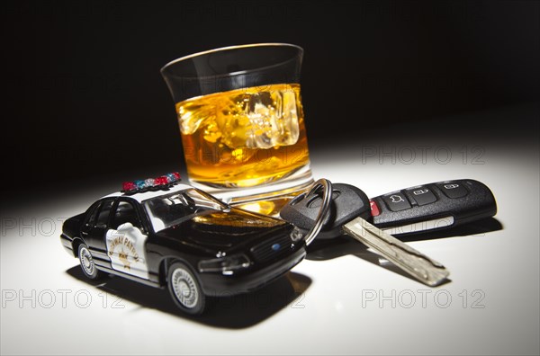Highway patrol police car next to alcoholic drink and keys under spot light