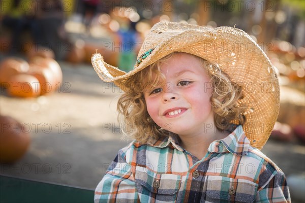 Adorable little boy wearing cowboy hat at pumpkin patch farm