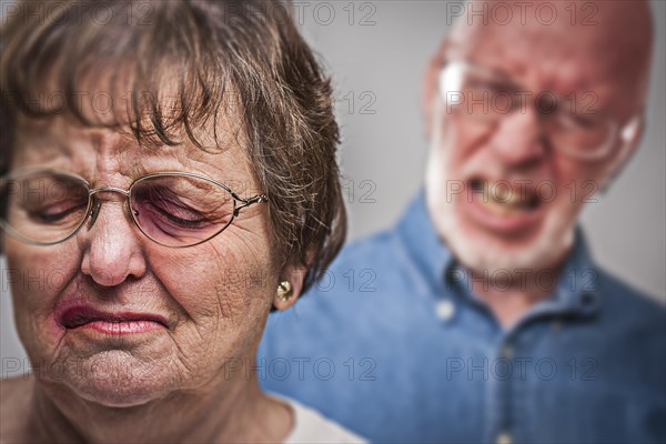 Battered and scared woman with ominous angry man behind