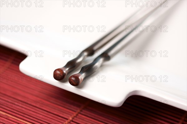 Wooden chopsticks & white plate on bamboo placemat