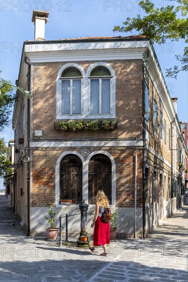 Tourist in red dress in front of a house