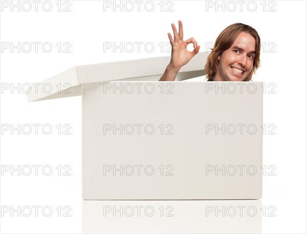 Young man with okay hand signal and popping his head from blank white box isolated on a white background