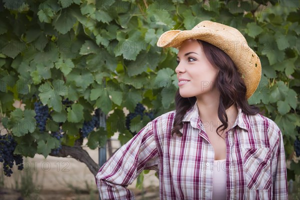 Young mixed-race adult female portrait outside wearing cowboy hat in vineyard