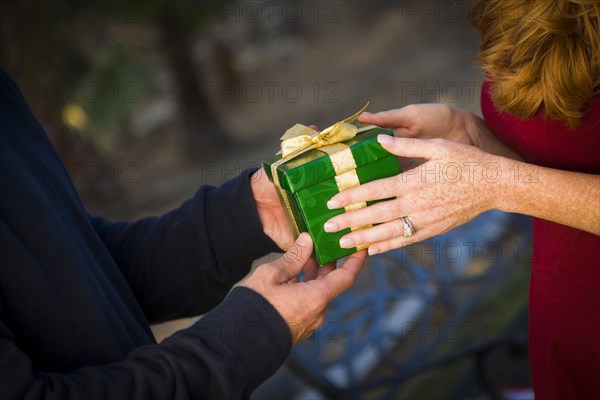 Hands of man and woman exchanging a wrapped christmas gift