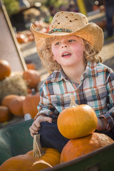 Adorable little boy wearing cowboy hat at pumpkin patch farm