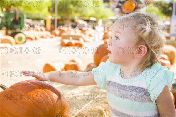 Adorable baby girl having fun in a rustic ranch setting at the pumpkin patch