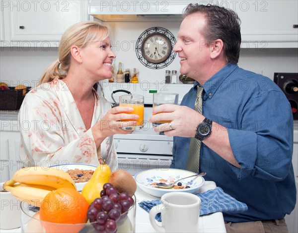 Happy attractive woman and businessman in kitchen with their orange juice and breakfast