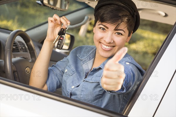 Happy smiling mixed-race woman in car with thumbs up holding set of keys