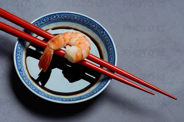 Cooked shrimp on chopsticks and shell with soy sauce