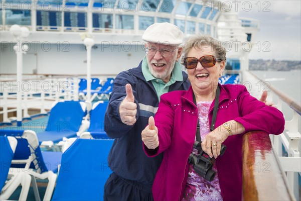 Happy senior couple with A thumbs up on the deck of A luxury passenger cruise ship