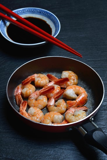 Fried prawns in pan and small bowl with soy sauce