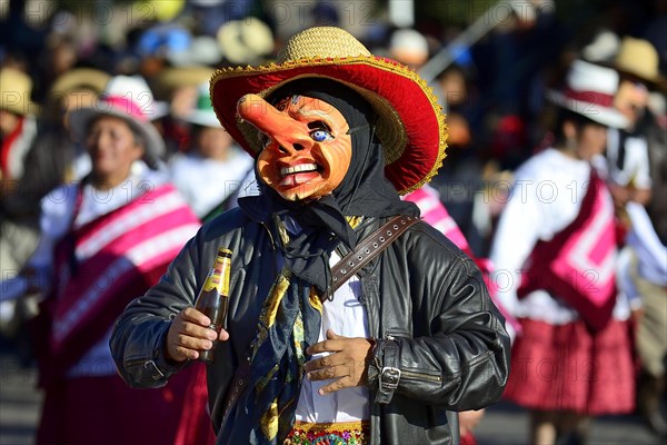 Mask of a man with a beer bottle at the parade on the eve of Inti Raymi