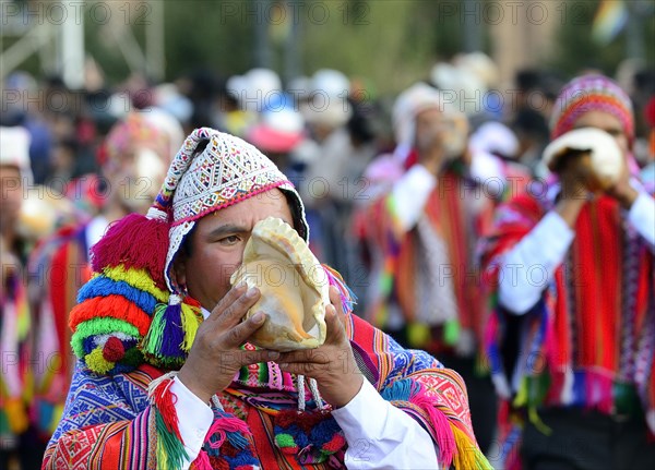 Indigenous man blows conch shell during parade on eve of Inti Raymi